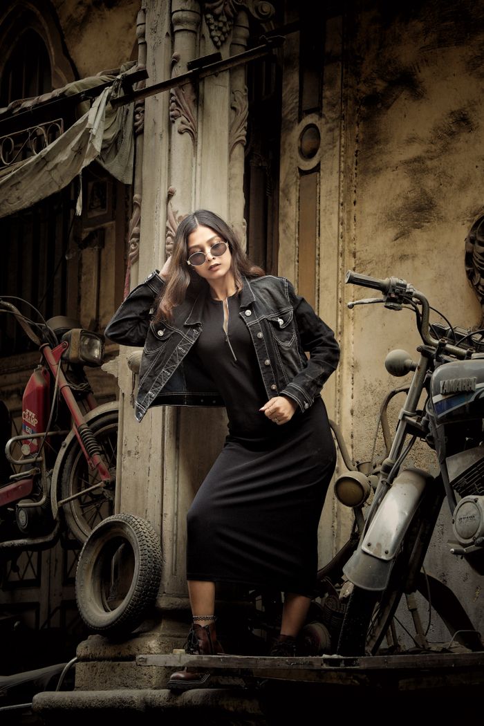 Stylish woman posing in urban alleyway with vintage motorcycles. Edgy and fashionable.